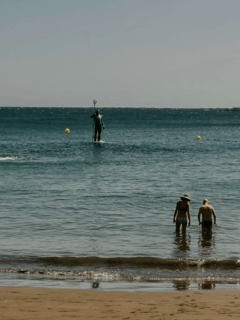 Statua del dio Neptuno a Playa Melenara, Gran Canaria con bagnanti