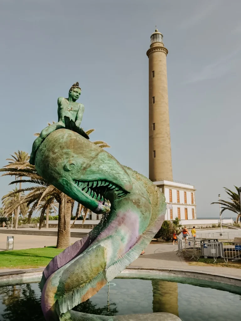 Il faro di Maspalomas dietro la fontana con la scultura di un pesce