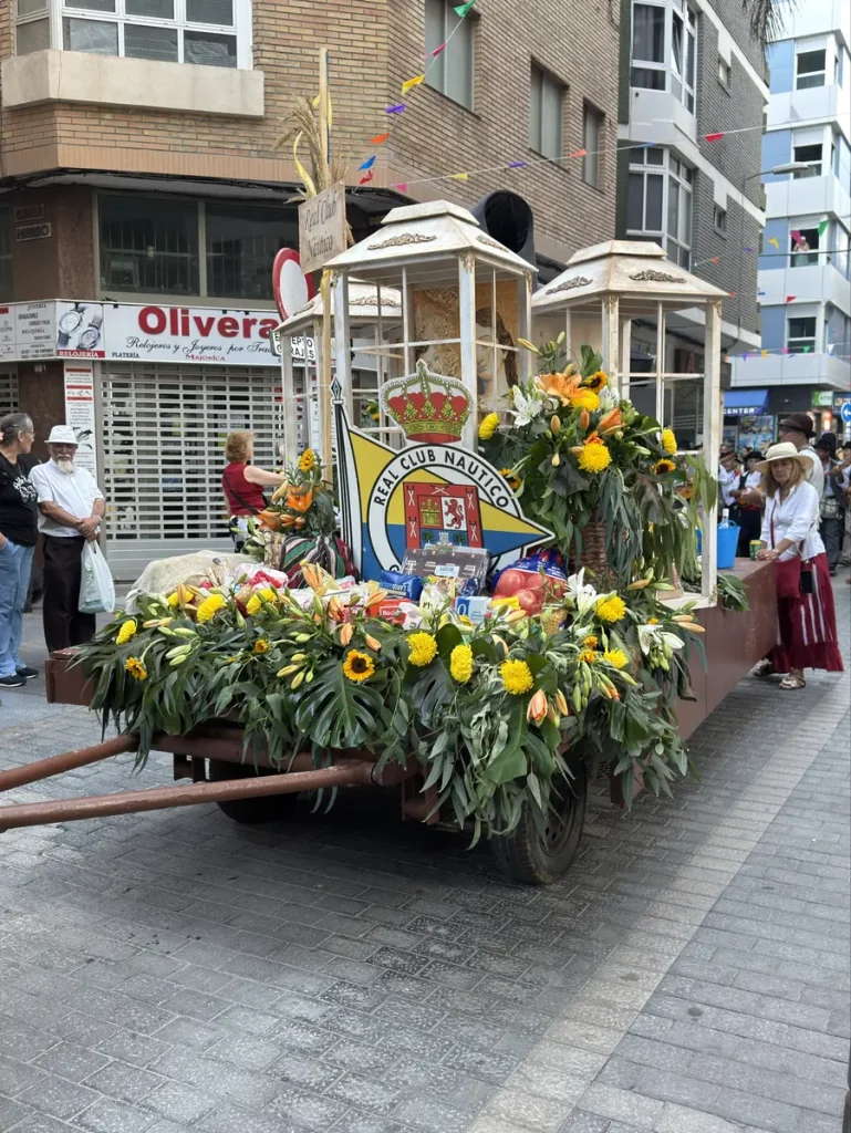 Carro della romería di Las Palmas decorato con fiori e generi alimentari, con lo stemma del Real Club Náutico