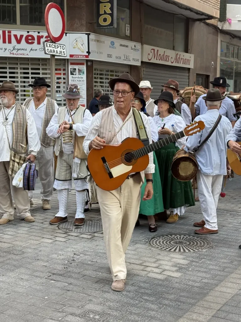 Uomo con la chitarra e gruppo folcloristico in abiti tradizionali durante la Romería-Ofrenda a Las Palmas