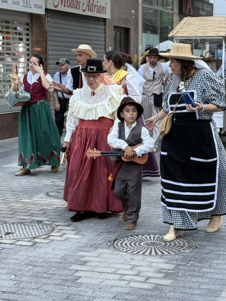 Gruppo in costume tradizionale canario con un bambino che suona uno strumento a corde alla romería di Las Palmas